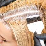 Hairdresser dyeing blonde hair roots